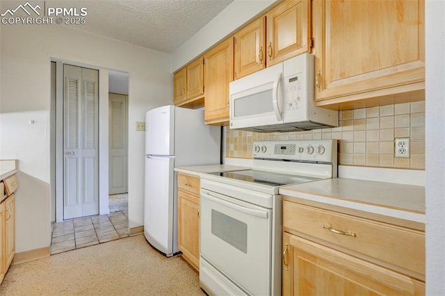 kitchen featuring white appliances, a textured ceiling, light brown cabinetry, and light countertops