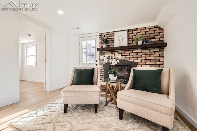 living area featuring visible vents, wood finished floors, recessed lighting, baseboards, and a brick fireplace