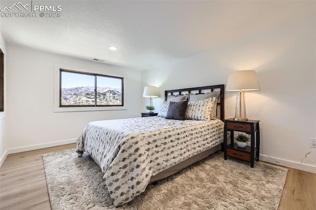 bedroom with visible vents, baseboards, and wood finished floors