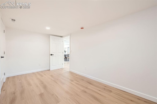 unfurnished room featuring light wood finished floors, visible vents, and baseboards