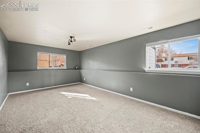 unfurnished room featuring a wealth of natural light, baseboards, and carpet floors