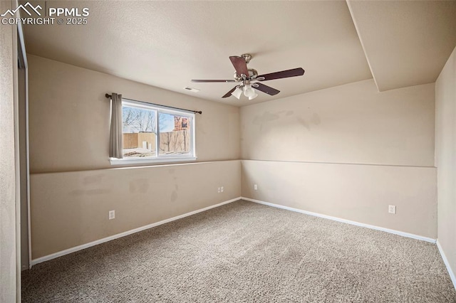 carpeted spare room with visible vents, a ceiling fan, and baseboards