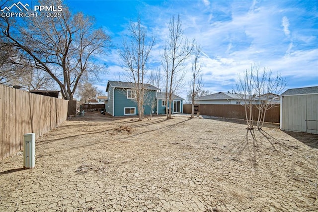 rear view of house featuring a storage shed, an outdoor structure, and a fenced backyard