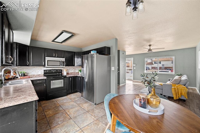 kitchen featuring dark cabinetry, light countertops, appliances with stainless steel finishes, and a sink