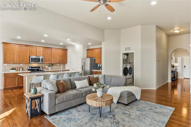 living room with visible vents, arched walkways, wood finished floors, and washer and clothes dryer