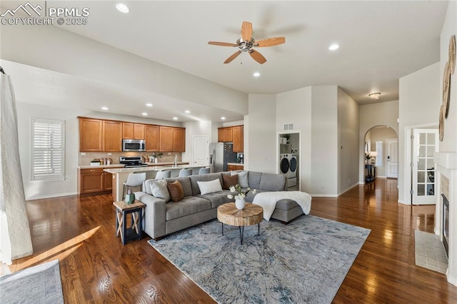 living area with dark wood-type flooring, washer and clothes dryer, recessed lighting, arched walkways, and baseboards