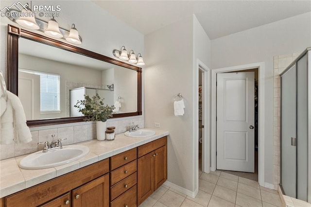 bathroom with double vanity, tile patterned floors, a stall shower, and a sink