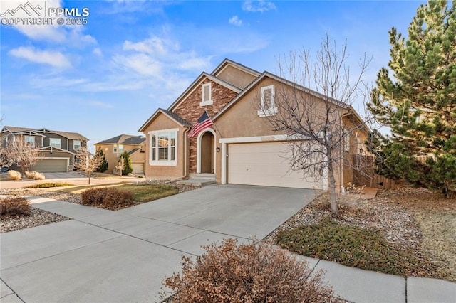 view of front of property featuring concrete driveway, an attached garage, stone siding, and stucco siding