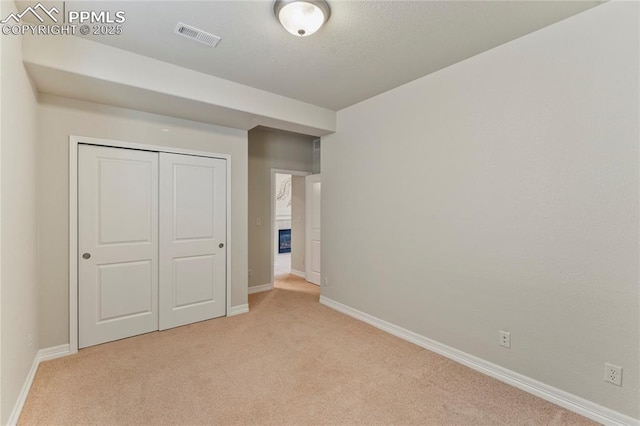 unfurnished bedroom with visible vents, baseboards, a closet, and carpet flooring