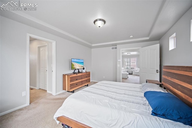 bedroom featuring light colored carpet, a raised ceiling, baseboards, and visible vents