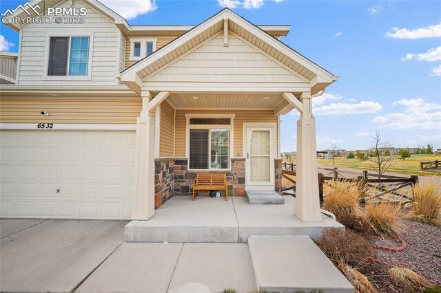 exterior space featuring covered porch, driveway, a garage, and stone siding