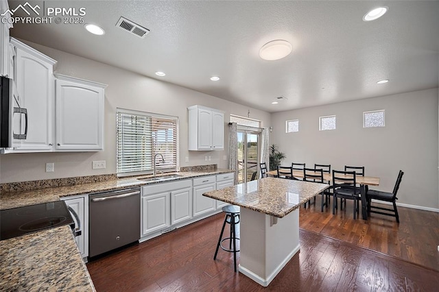 kitchen with a breakfast bar area, a sink, white cabinetry, visible vents, and appliances with stainless steel finishes