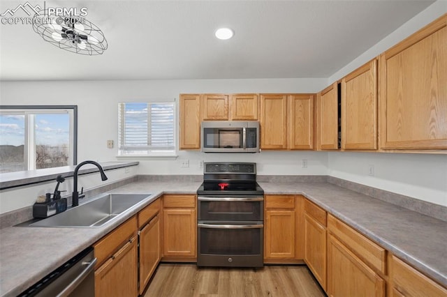 kitchen with recessed lighting, a sink, stainless steel appliances, light countertops, and light wood-type flooring