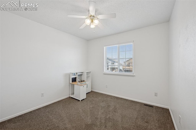 spare room featuring baseboards, visible vents, ceiling fan, a textured ceiling, and dark carpet