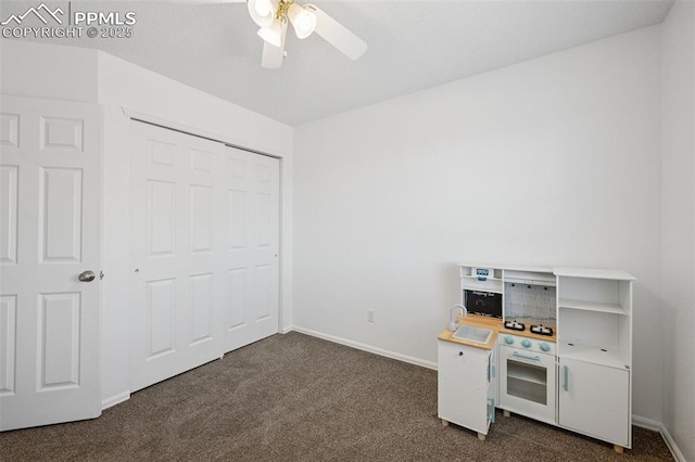 interior space with a ceiling fan, baseboards, and dark carpet