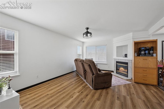 living room with wood finished floors, baseboards, and a tile fireplace