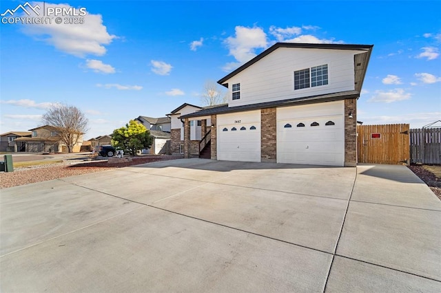 view of front of house featuring brick siding, concrete driveway, an attached garage, and fence