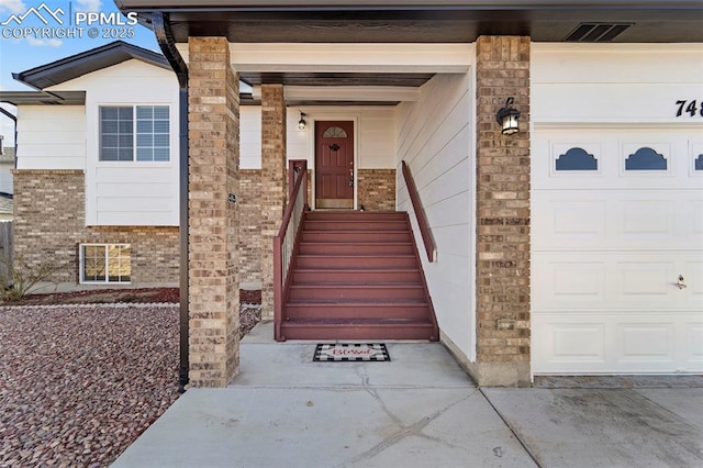 view of exterior entry featuring visible vents, brick siding, and an attached garage