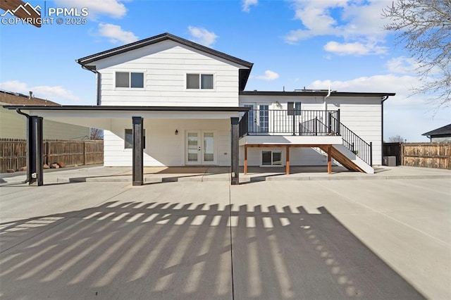 rear view of house with stairs, a patio area, fence, and french doors