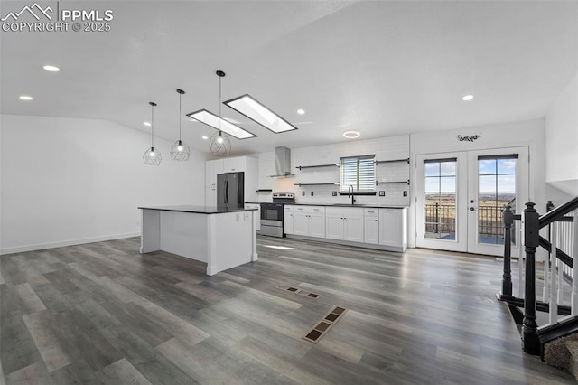 kitchen featuring stainless steel electric stove, freestanding refrigerator, a sink, dark countertops, and wall chimney exhaust hood