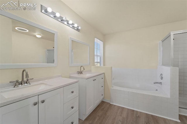 bathroom with a sink, a garden tub, wood finished floors, and a tile shower