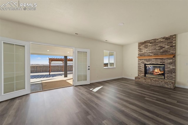 unfurnished living room featuring french doors, baseboards, wood finished floors, and a fireplace