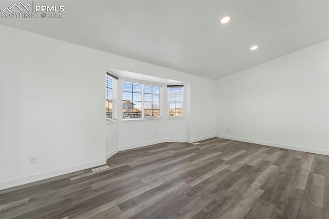 spare room featuring dark wood-type flooring, recessed lighting, and baseboards