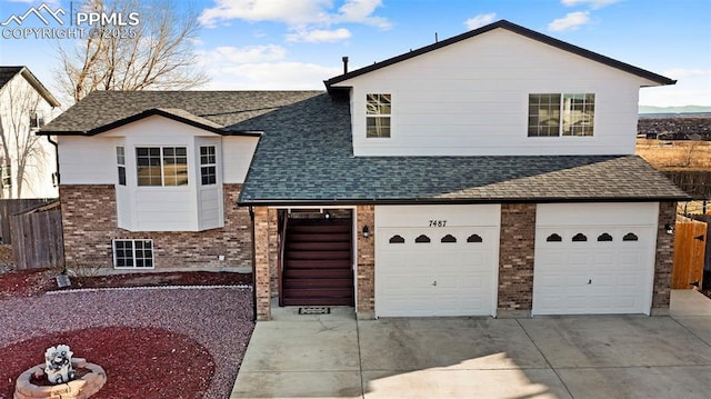 view of front of home with fence, roof with shingles, concrete driveway, a garage, and brick siding