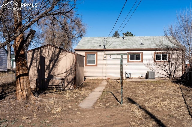 back of house with a storage shed, central air condition unit, and an outbuilding