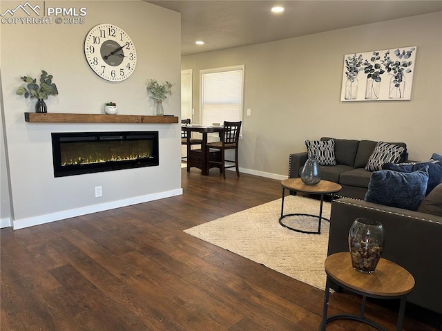 living area with a glass covered fireplace, recessed lighting, wood finished floors, and baseboards