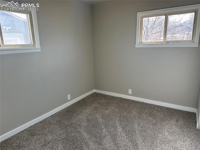 empty room with dark colored carpet and baseboards