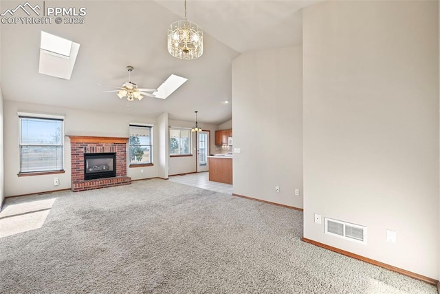 unfurnished living room featuring vaulted ceiling with skylight, visible vents, light colored carpet, and baseboards