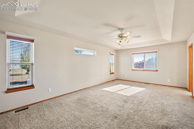 spare room with light carpet, visible vents, baseboards, and a tray ceiling