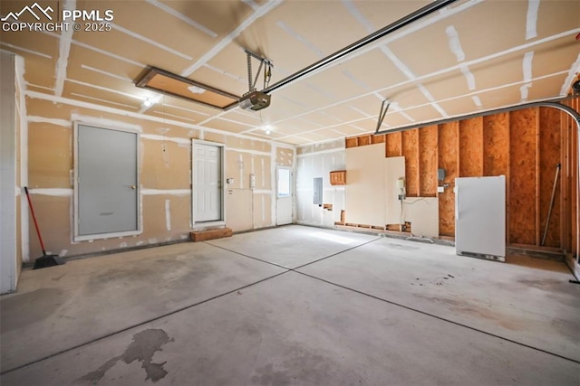 garage featuring freestanding refrigerator, a garage door opener, and electric panel