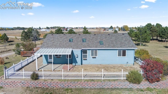 rear view of house featuring a fenced front yard and roof with shingles