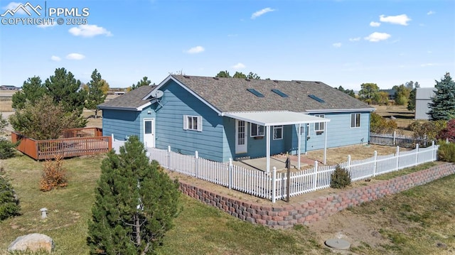 view of front of house featuring a front lawn, a fenced backyard, a shingled roof, a wooden deck, and a patio area