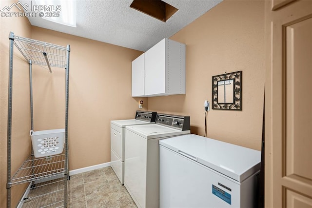 laundry area with washer and dryer, baseboards, cabinet space, and a textured ceiling