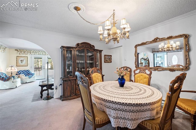 carpeted dining room with arched walkways, a textured ceiling, a chandelier, and ornamental molding