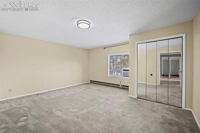 unfurnished bedroom with a baseboard heating unit, carpet flooring, baseboards, and a textured ceiling