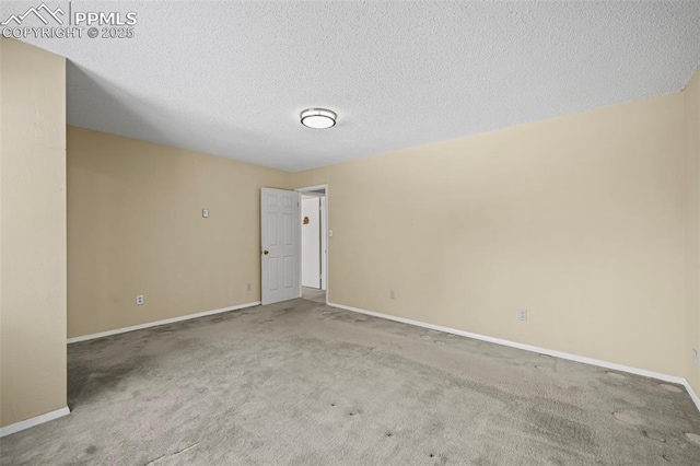 unfurnished room with carpet flooring, a textured ceiling, and baseboards