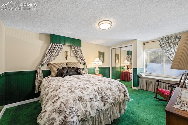 carpeted bedroom with a textured ceiling, a closet, and wainscoting