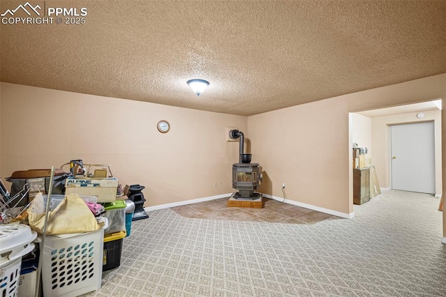 interior space featuring a textured ceiling, a wood stove, baseboards, and carpet floors