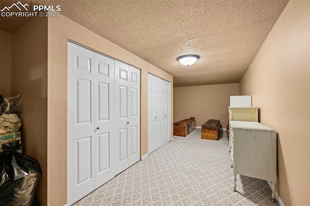 interior space featuring baseboards, multiple closets, and a textured ceiling