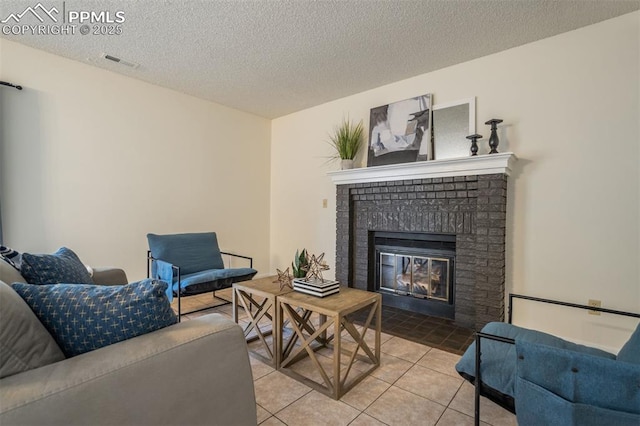 tiled living area featuring visible vents, a fireplace, and a textured ceiling