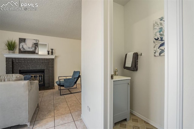 living room featuring light tile patterned floors, a fireplace, baseboards, and a textured ceiling