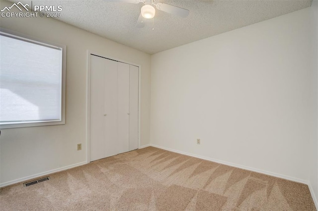 unfurnished bedroom featuring visible vents, a textured ceiling, a closet, carpet flooring, and baseboards