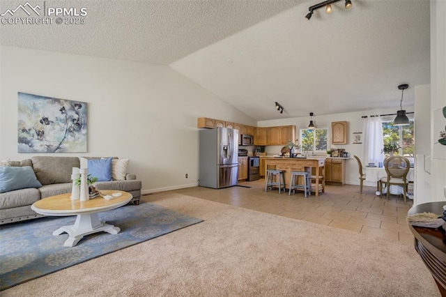 living room with lofted ceiling, a textured ceiling, light tile patterned flooring, baseboards, and light colored carpet