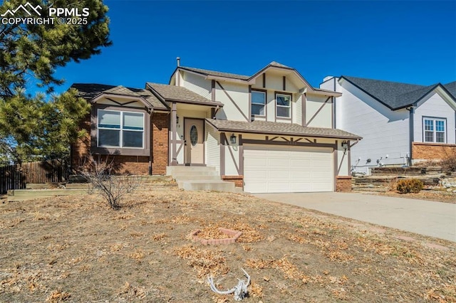 english style home featuring brick siding, an attached garage, concrete driveway, and fence