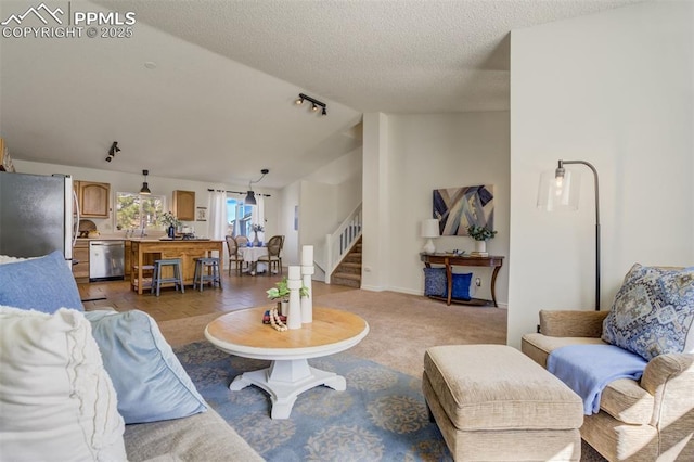 living area featuring a textured ceiling, stairway, baseboards, vaulted ceiling, and light carpet