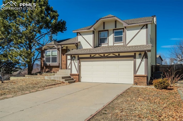 tudor home featuring stucco siding, driveway, fence, a garage, and brick siding